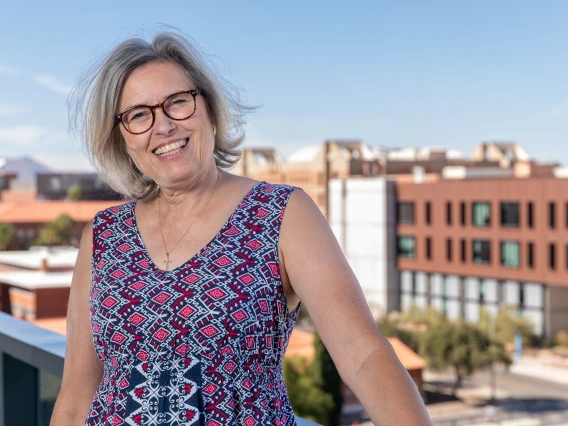 Leanne Scott, member of the Parent & Family Association Board standing on a balcony, over looking the University of Arizona Campus at the western skyline.