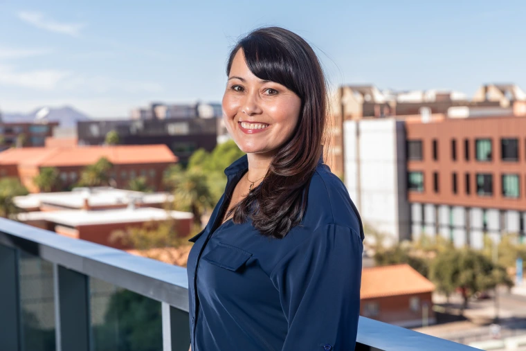 Candace Geary, co-chair of the Parent & Family Association is standing on the balcony at the University of Arizona campus overlooking the western skyline