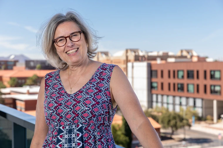 Leanne Scott, member of the Parent & Family Association Board standing on a balcony, over looking the University of Arizona Campus at the western skyline.